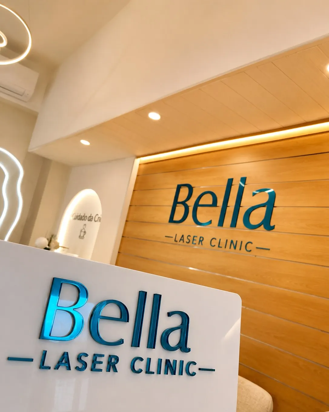 Balcão de receção da Bella Laser Clinic, com o logótipo em relevo sobre painel de madeira
